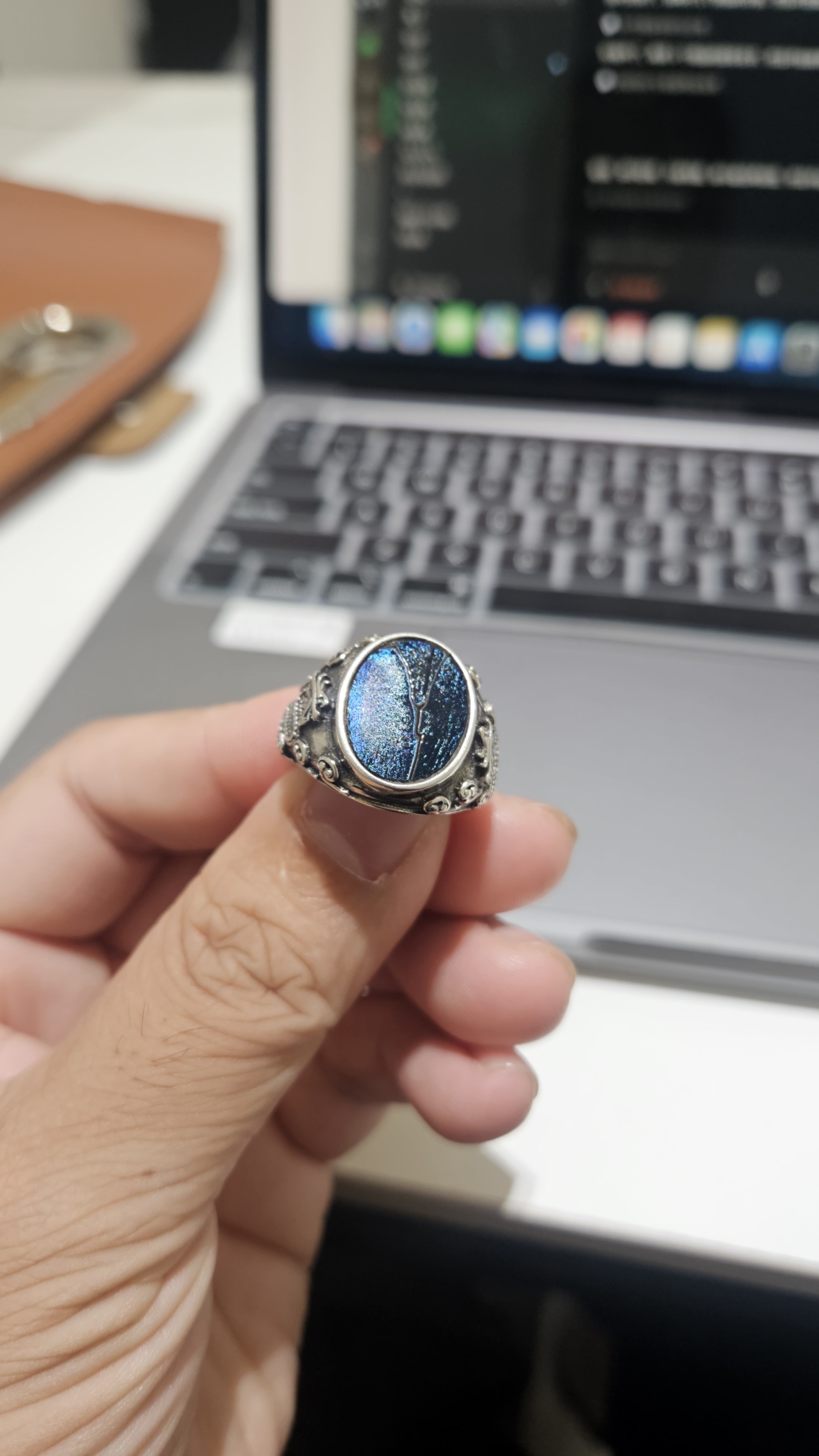 A hand holding a Luminya silver ring with blue Jianzhan glaze, its glaze still carrying the fire
